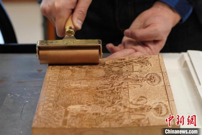 圖為徐晉林工作室工作人員正在給雕好壁畫的版面滾油墨?！【琶赖┰?　攝