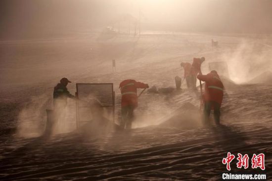 圖為敦煌市鳴沙山月牙泉景區(qū)“駱駝保姆”清理駱駝糞便。　張曉亮 攝