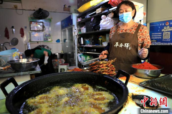 圖為平安驛·河湟民俗文化體驗地內(nèi)的商戶炸干板魚?！⊙Φ?攝